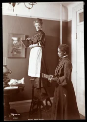 Madge Carr Cook che appende quadri con la sua cameriera, c.1904